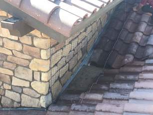 Pigeon netting around stone chimney and roof tiles